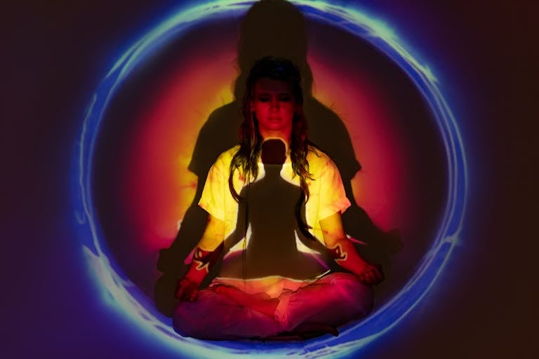 Woman in yellow jacket and blue denim jeans sitting on a blue inflatable ring, surrounded by her electromagnetic aura field.